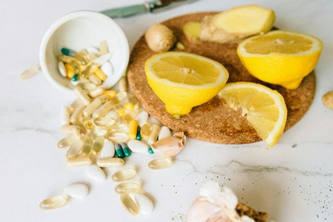 Immune support dietary supplements, vitamin capsules, fresh lemons, and ginger for VivoNu wellness products